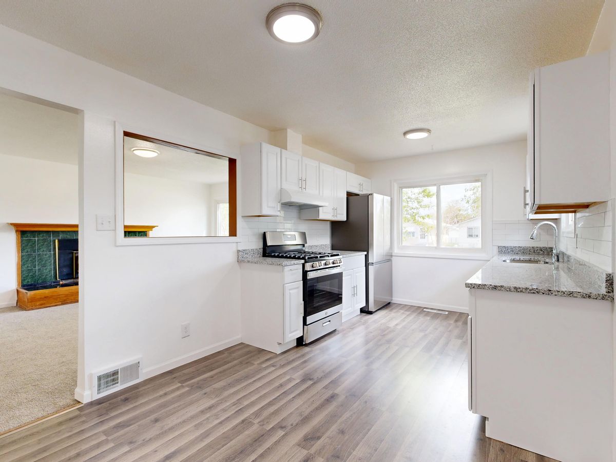 Finished kitchen remodel with white cabinets, granite counters and new plank flooring